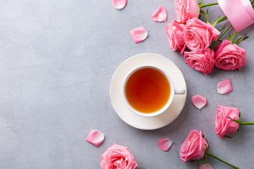 Cup of tea with pink rose. Top view. Copy space. Grey stone background