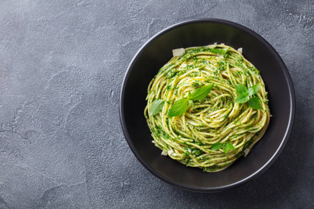 istock Pasta spaghetti with pesto sauce in black bowl. Grey background. Copy space. Top view. 1174658619