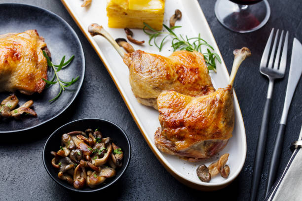 Duck legs confit with potato gratin and mushroom on a plate. Close up. stock photo