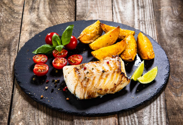 istock Fried cod fillet with baked potatoes and vegetables 1174659673