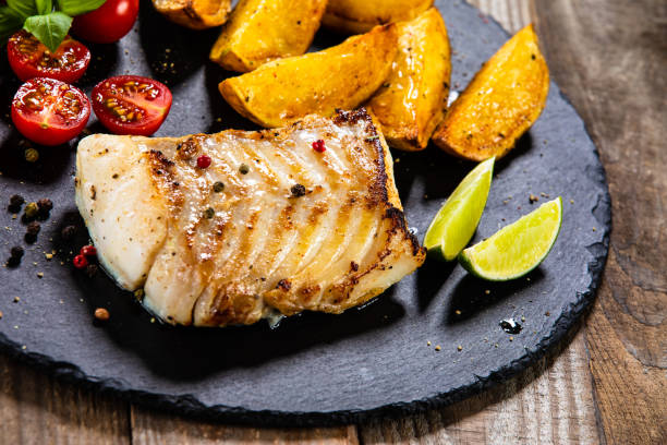 istock Fried cod fillet with baked potatoes and vegetables 1174659774