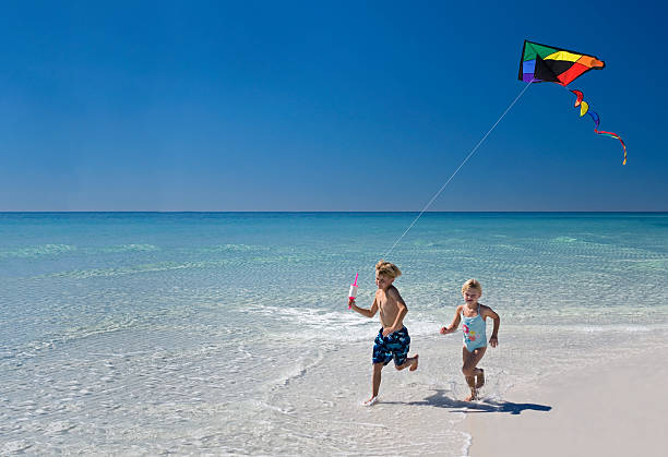 Boy & Girl Flying A Kite At The Beach stock photo