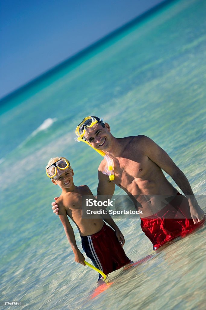 Padre e figlio In piedi In acqua presso la spiaggia - Foto stock royalty-free di Spiaggia