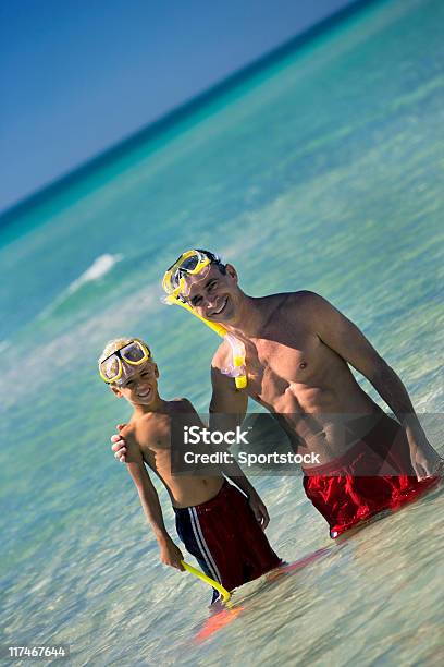 Padre E Figlio In Piedi In Acqua Presso La Spiaggia - Fotografie stock e altre immagini di Spiaggia