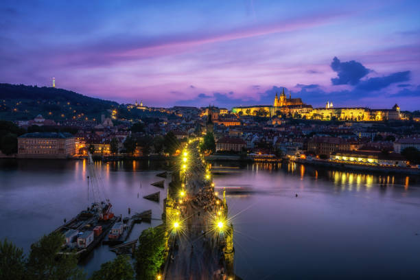 charles bridge and prague castle view sunset over the Charles bridge and prague castle all illumiated with pink sky reflecting on the vltava river below viewed from the old town tower observatory deck. old town bridge tower stock pictures, royalty-free photos & images
