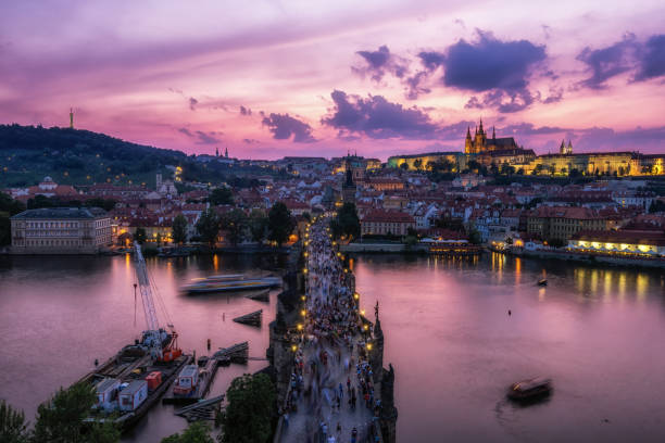charles bridge and prague castle view sunset over the Charles bridge and prague castle all illumiated with pink sky reflecting on the vltava river below viewed from the old town tower observatory deck. old town bridge tower stock pictures, royalty-free photos & images