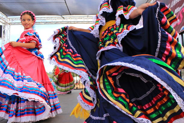 Young girls performing traditional Mexican dance Young girls on a stage, wearing colorful, pretty skirts and dresses, are performing a traditional Mexican dance. beautiful mexican girls stock pictures, royalty-free photos & images