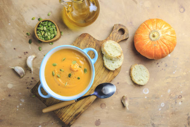 istock Pumpkin soup and organic pumpkins on rustic table. 1174682432