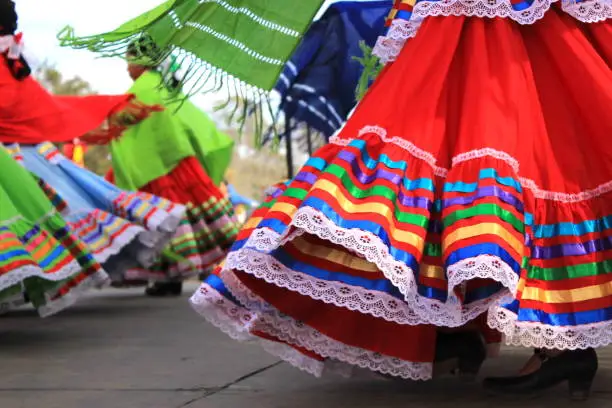 Close up of colorful skirts flying during traditional Mexican dancing. Young girls perform on a stage during an event celebrating Latino culture and heritage.