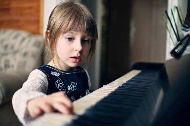 Cute little girl aged 4 is playing the old piano.