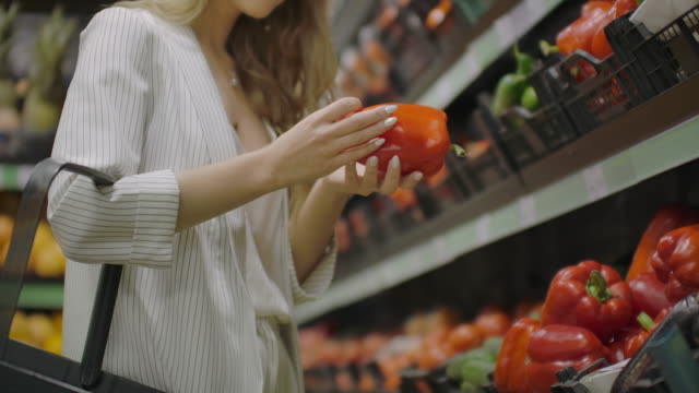 Hands take few colorful pepper one by one in marketplace and hold. Close up concept of selection, buy quality fruit or red vegetables. Young woman pick up some tasty freshness ingredient for cooking.