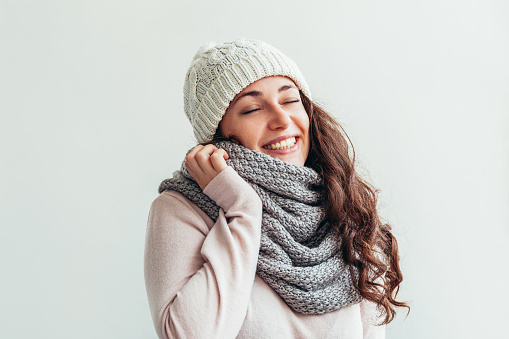 Beautiful woman winter portrait, true emotions. Laughing girl with long hair wearing warm clothes hat scarf isolated on white background. Young hipster girl looking happy and excited, having fun