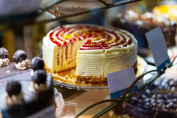 A spongecake with raspberries is on display with one piece already taken revealing its layered inner part.