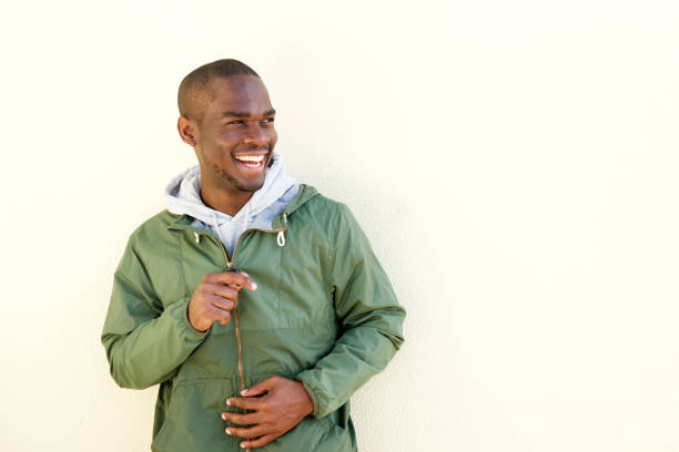 african american male model smiling with jacket by wall Portrait of african american male model smiling with jacket by wall wind shelter stock pictures, royalty-free photos & images