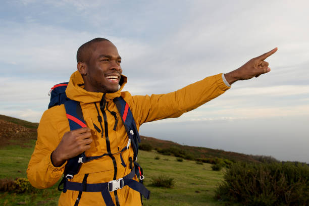 istock happy african american hiker pointing finger outdoors in nature 1174712677
