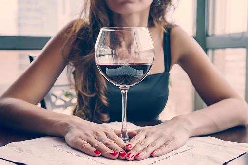 Closeup portrait of young female customer drinking red wine with eyes closed. Woman drinking wine, taking a SIP from a glass glass. Wine tasting in the restaurant.