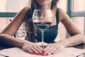 Closeup portrait of young female customer drinking red wine with eyes closed. Woman drinking wine, taking a SIP from a glass glass. Wine tasting in restaurant.