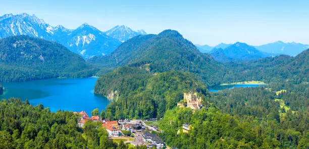 Landscape with Hohenschwangau Castle, Bavaria, Germany. Beautiful panorama of mountain lakes. Scenery of Alpine nature in summer. Aerial scenic view of village in Alps. Travel and vacation concept.