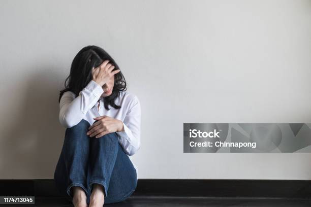 Anxiety Disorder Menopause Woman Stressful Depressed Panic Attack Person With Mental Health Illness Headache And Migraine Sitting With Back Against Wall On The Floor In Domestic Home Stock Photo - Download Image Now