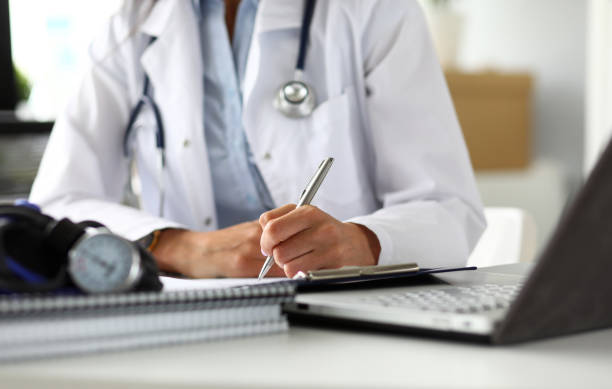 istock Hands of female GP making notes with silver pen 1174713075