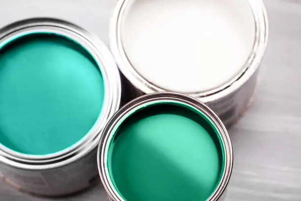 Photo of Several opened cans with green paint inside.