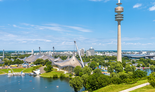 Munich, Germany - Aug 2, 2019: Munich Olympiapark in summer, Germany. It is the Olympic Park, landmark of Munich. Scenic view of former sport area from above. Cityscape of Munich with communication tower. Skyline of Munich city.