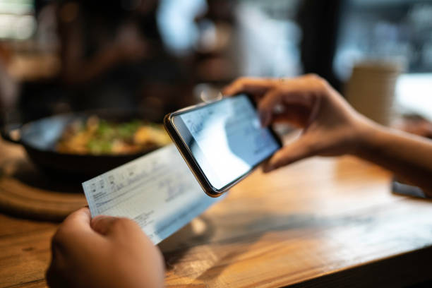 hombre depositando cheque por teléfono en el restaurante - aplicación para móviles fotos fotografías e imágenes de stock