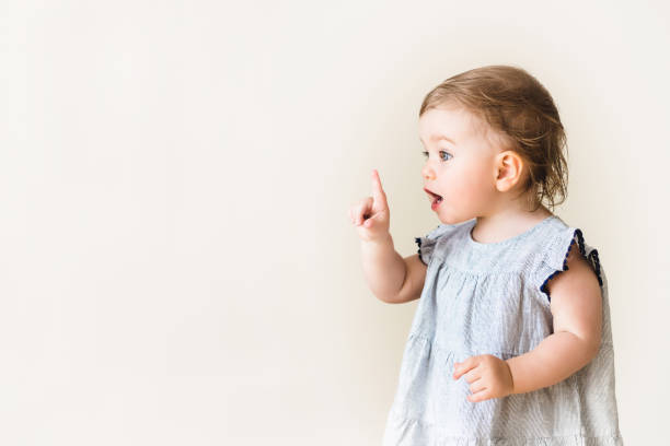 baby-mädchen zeigt ihren finger, aufgeregt und emotional, auf neutralen hintergrund - cute girl stock-fotos und bilder