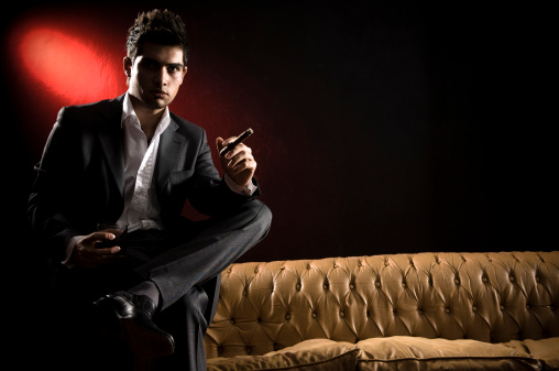 Jacket weared young man sitting on a cream leather seat and smoking.