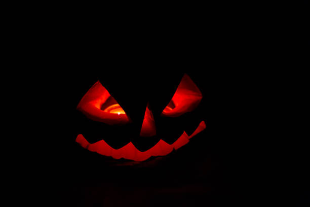 istock Spooky Halloween pumpkin jack-o-lantern with burning candles on dark background 1174742165