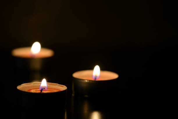 istock Three burning candles close up in the darkness. Mystery background 1174766445