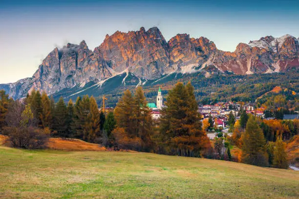 Photo of Admirable alpine cityscape with high mountains at sunset, Dolomites, Italy