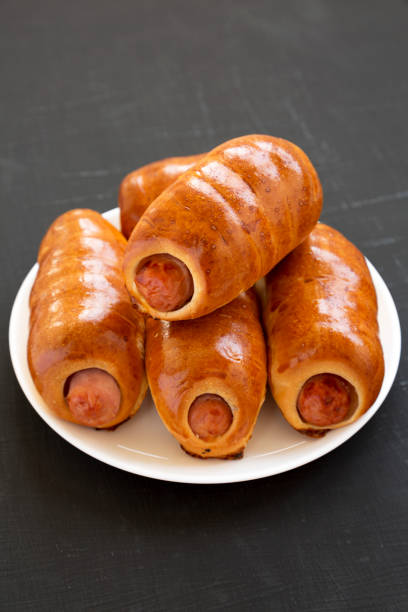 istock Homemade beef sausage kolache on a white plate on a black background, low angle view. Close-up. 1174768405