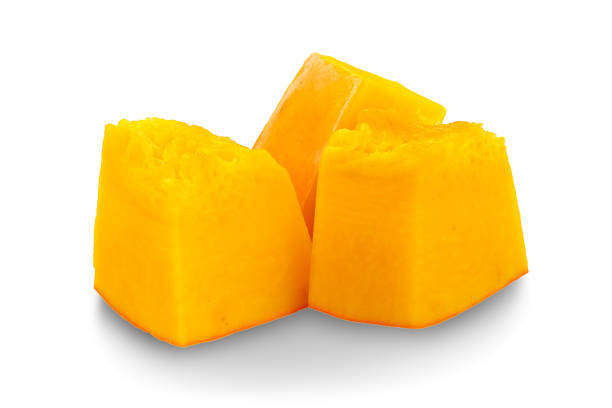 Sliced pumpkin isolated on white. Pieces of pumpkin, side view. Diced orange pumpkin, closeup.