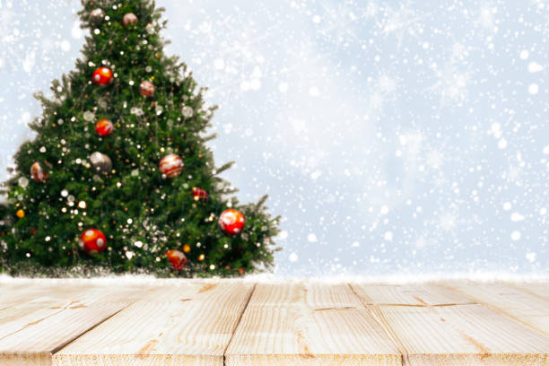 istock Top of empty wood table with beautiful Christmas tree and snowfall  backdrop 1174769472