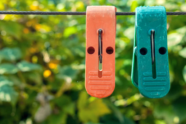 Two Plastic Clothespins on Clothes Line on Blurred Green Leaves Background on a Sunny Summer Day.