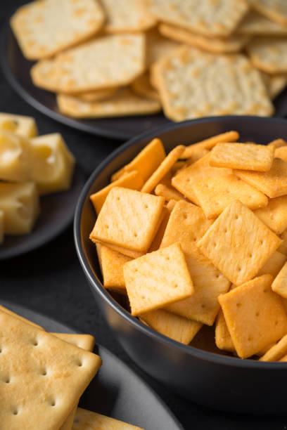 istock Crackers in bowl with cheese on a dark plate a black background. 1174776268