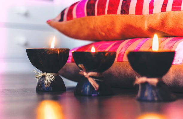 istock Burning spa aroma candles in coconut shell and  burgundy pillows with pattern, cozy home interior background 1174777396