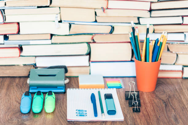 istock School stationery accessories - notebook, copybook stack with plastic holder pencils, pens, markers, paper clips, stickers, notepads, sharpener with stack of books education concept background 1174777704