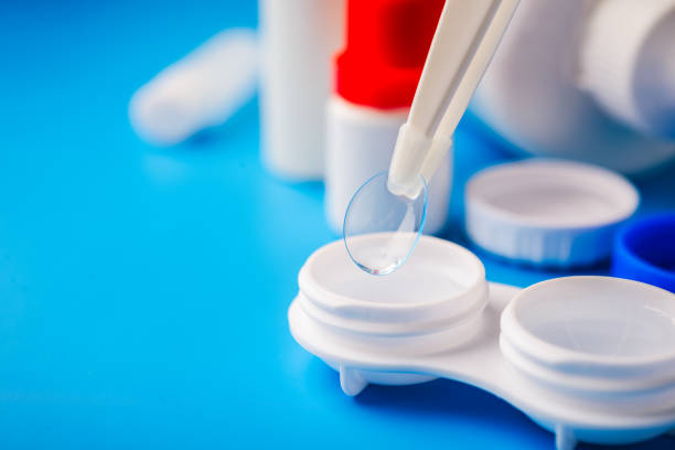 istock Optical corrective medical soft contact lenses for eyes in white plastic case with storage solution, accessories and care products in plastic bottles on blue background, Cleaning 1174780951