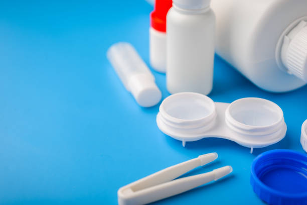 istock Optical corrective medical soft contact lenses for eyes in white plastic case with storage solution, accessories and care products in plastic bottles on blue background, Cleaning 1174781113