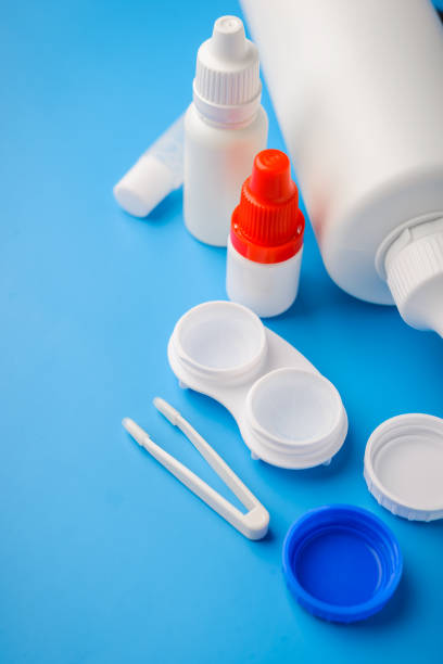 istock Optical corrective medical soft contact lenses for eyes in white plastic case with storage solution, accessories and care products in plastic bottles on blue background, Cleaning 1174781125
