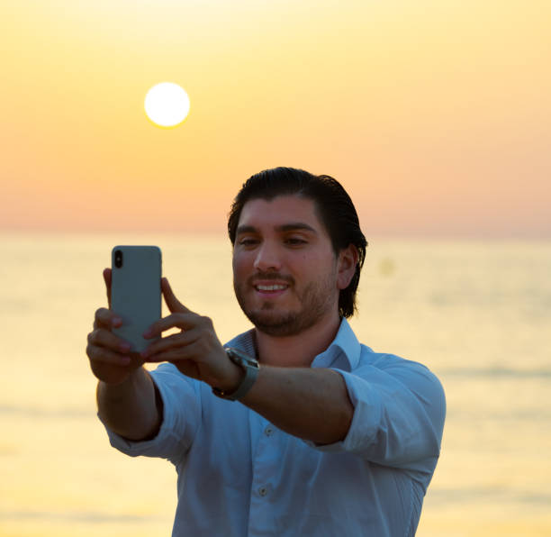 istock Man enjoying colorful sunset or sunrise, taking selfie 1174791888