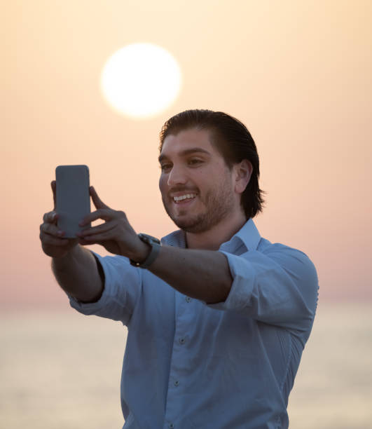 istock Man enjoying colorful sunset or sunrise, taking selfie 1174791893