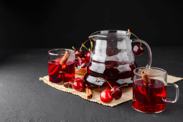 freshly brewed tea with cherries on a dark concrete background - flower cherry cup tea imagens e fotografias de stock