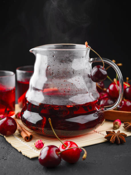freshly brewed tea with cherries on a dark concrete background - flower cherry cup tea imagens e fotografias de stock