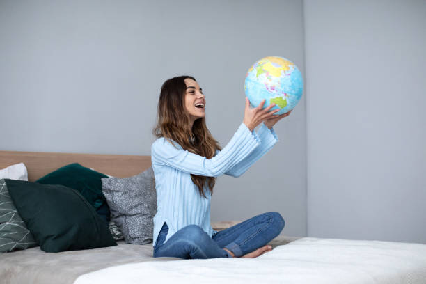 istock Happy woman holding a globe, indoor. 1174799104