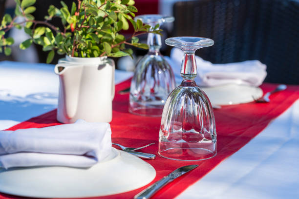 istock Elegant table setting with fork, knife, wine glass, white plate and red napkin in restaurant . Nice dining table set with arranged silverware and napkins for dinner 1174800941