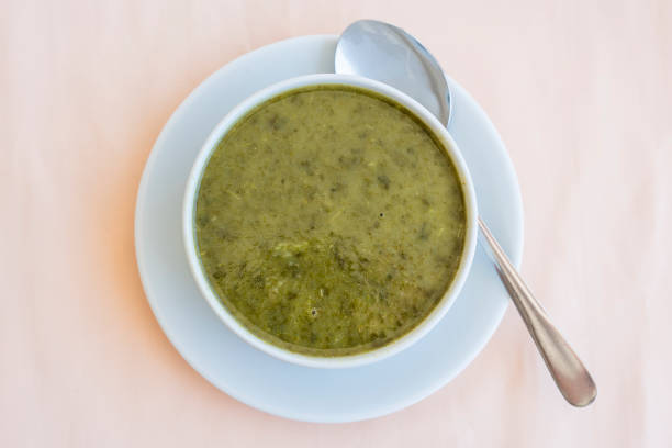 Green cream soup from spinach in white bowl, close up