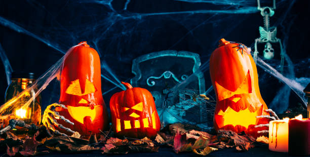 istock Halloween decor, Jack's Lantern band with glowing eyes, mystical glow, spider web,dry leaves, dark background, burning candles, skeleton bones 1174804814
